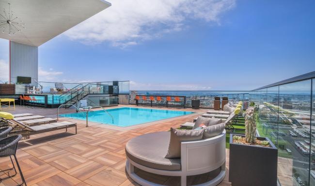 Relax and unwind poolside a deck with a pool and a city in the background